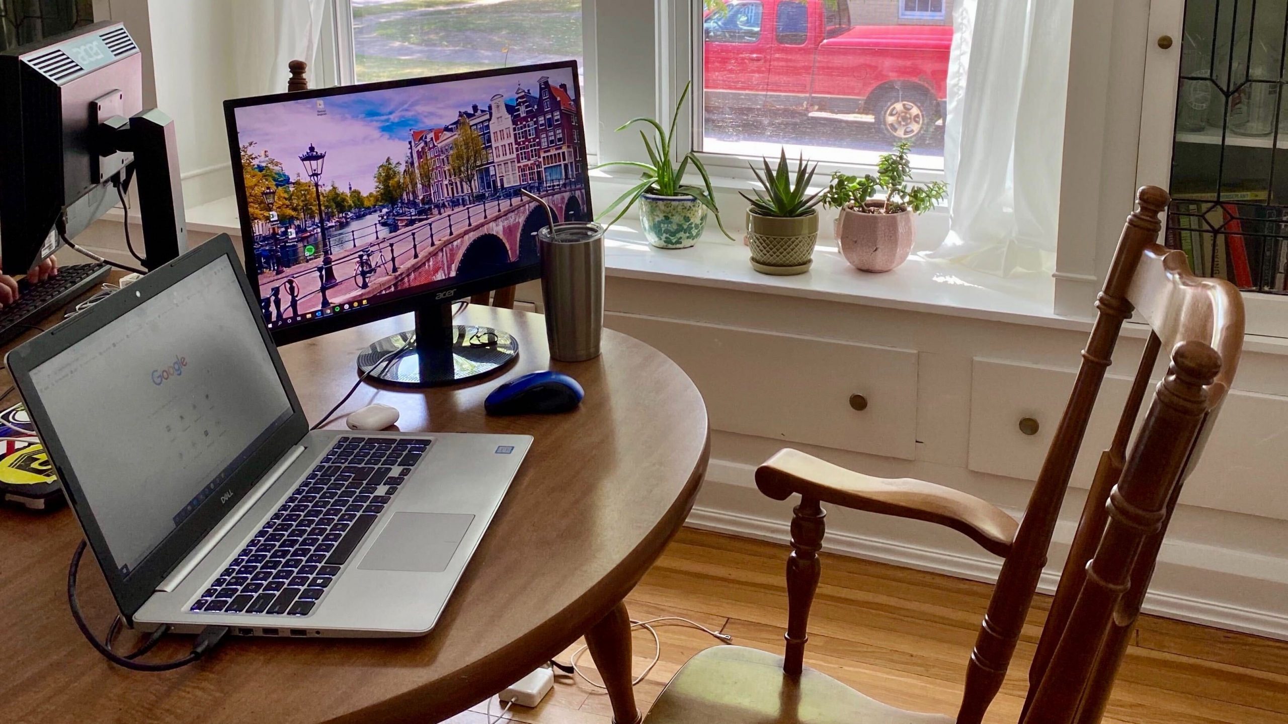 Image of a laptop and second monitor in front of a chair in a home setting.