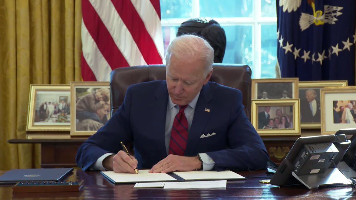 President Joe Biden signing an executive order in the Oval Office