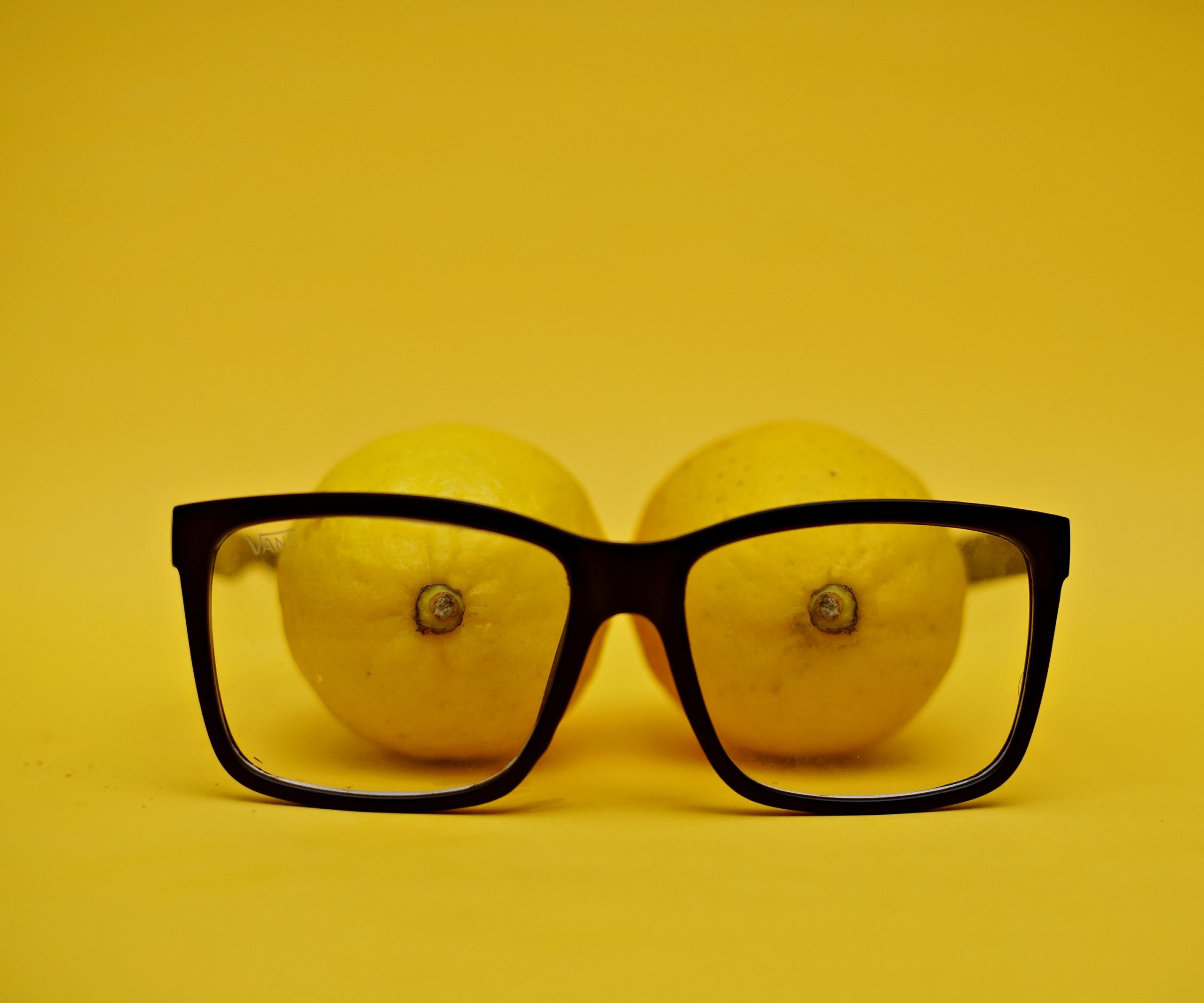 black framed glasses in front of 2 lemons